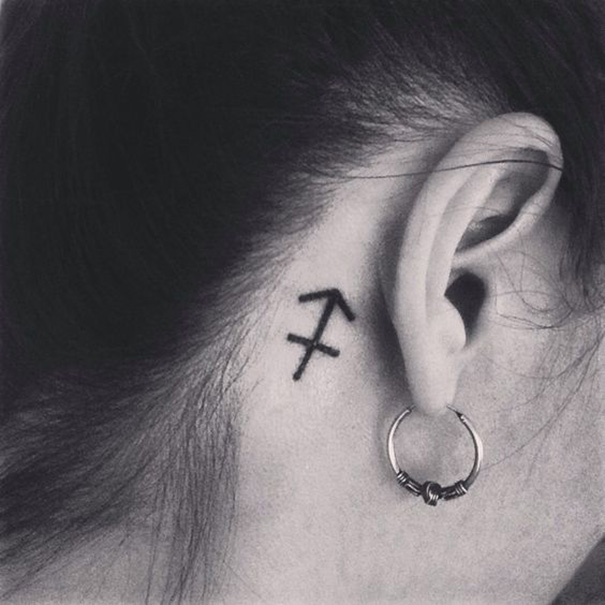 tatuagem de sagitário do zodíaco atrás da orelha 