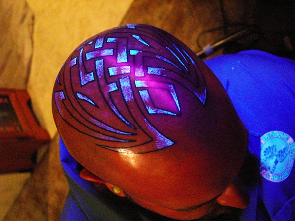 Uma tatuagem de caveira tribal feita por Richie Streate de Electric Soul Tattoo em Lancaster, Califórnia, com enchimento de tinta UV para trazer um padrão de tecer sob luz negra. 
