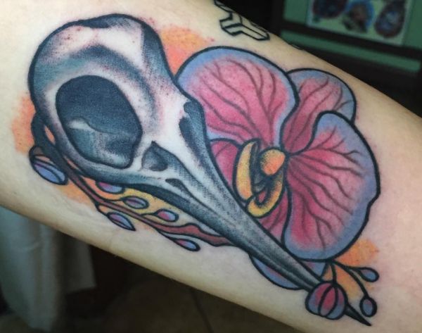 Tatuagem de orquídea com design de beija-flor caveira no braço 
