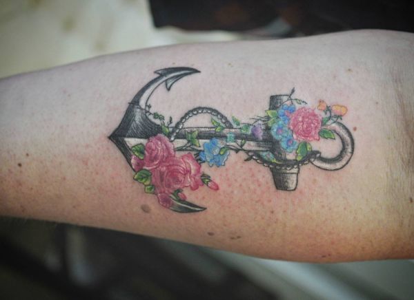Tatuagem de âncora com flores no antebraço 