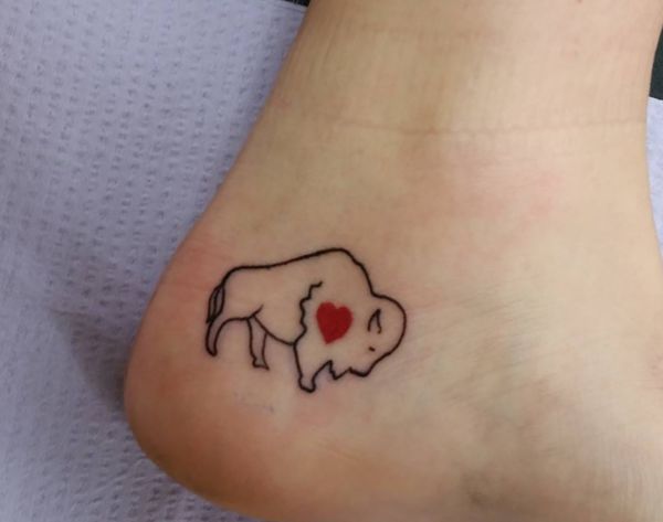 Pouco búfalo com desenho de tatuagem de coração no tornozelo 