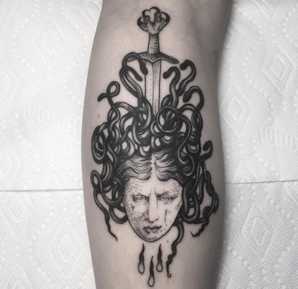 Medusa com tatuagem de espada na perna 
