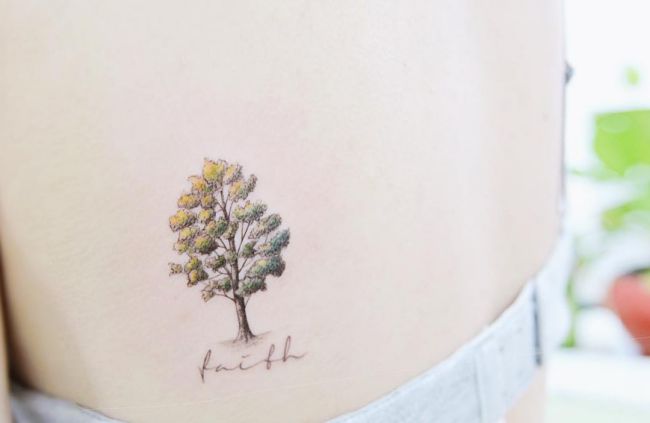 Pequena árvore com tatuagem de nome na escápula 