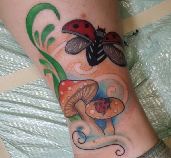 Joaninha com desenho de tatuagem de cogumelo na perna 