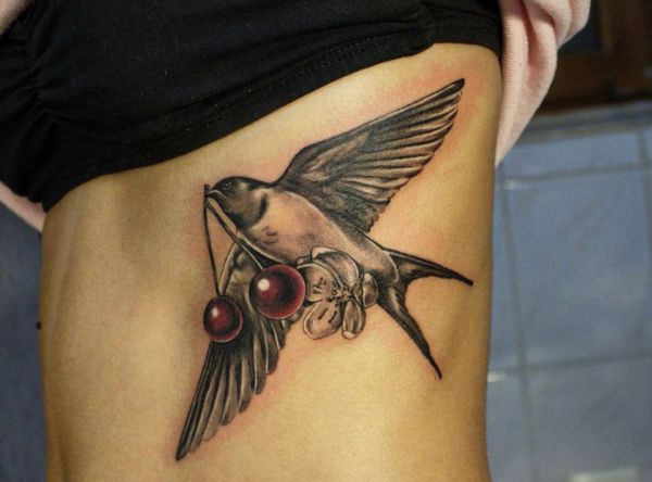 Tatuagem de andorinha com cereja nas costelas 