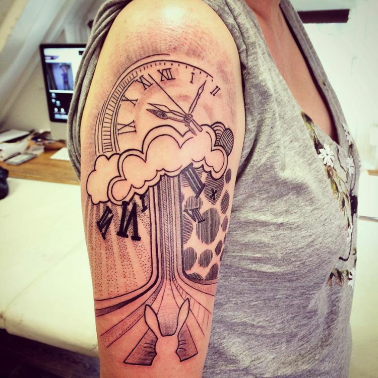 relógio de braços tatuados no ombro 