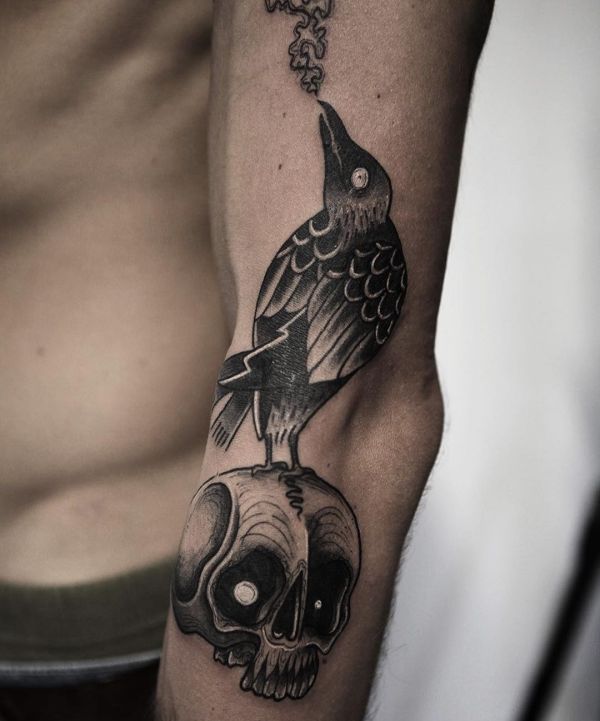 Crânio e desenho de tatuagem de corvo no braço 