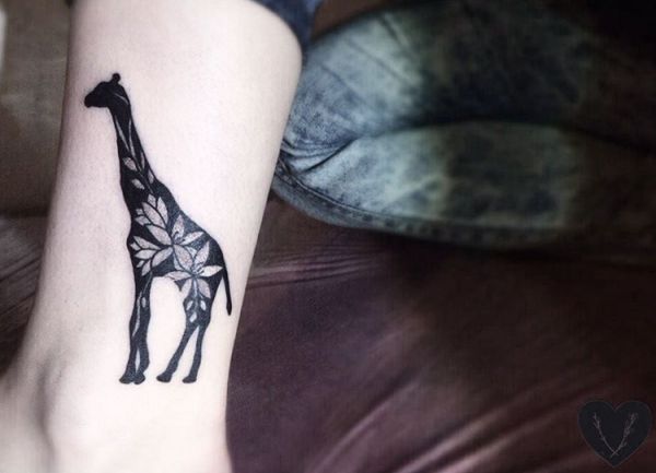 Desenho de tatuagem de girafa com flores na parte inferior da perna 