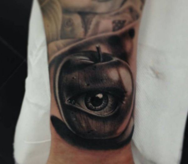 Maçã realista com design de tatuagem de olho no pulso 