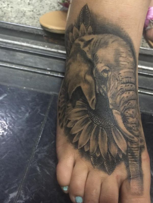 Tatuagem de cabeça de elefante com design de flor no pé 