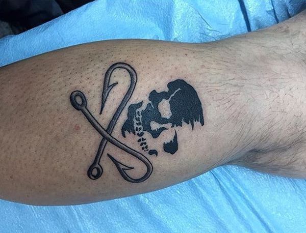 Tatuagem de dois ganchos com caveira na perna 