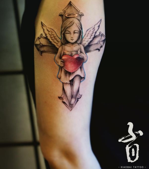 Anjo com coração e cruz tatuagem no braço