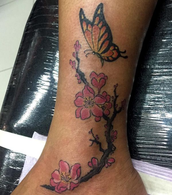 Borboleta com tatuagem de flores na parte inferior da perna 