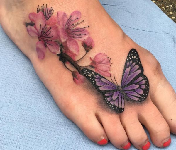Borboleta realista com tatuagem de flor de cerejeira no pé 