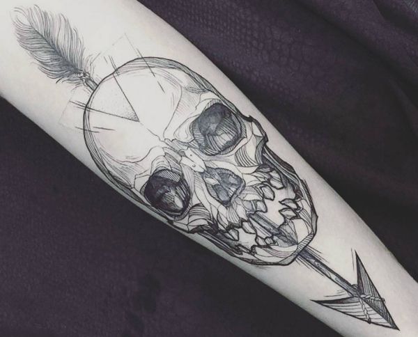 Crânio com desenho de tatuagem de seta no braço 