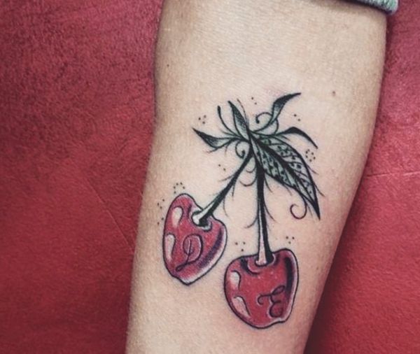 Tatuagem de cereja com iniciais no braço 