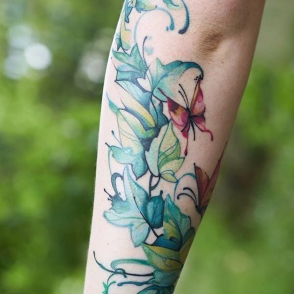 Desenho de tatuagem de hera em aquarela com borboleta no braço 