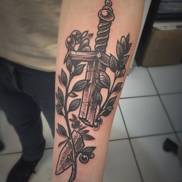Espada quebrada e desenho de ramo de oliveira no antebraço 