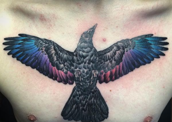 Tatuagem de corvo com penas coloridas no peito 