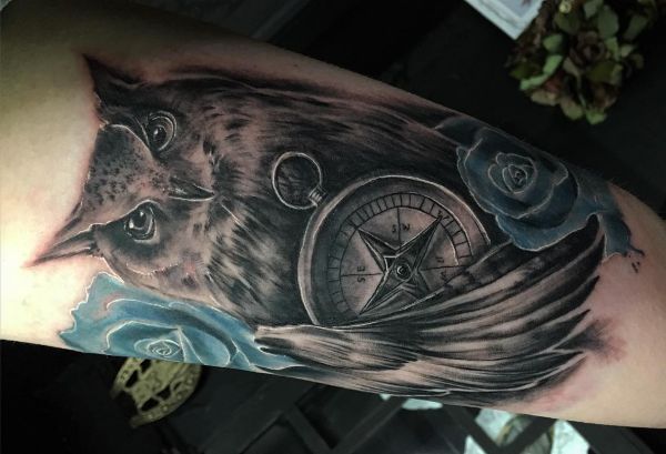 Bússola com tatuagem de coruja com rosa azul no braço 
