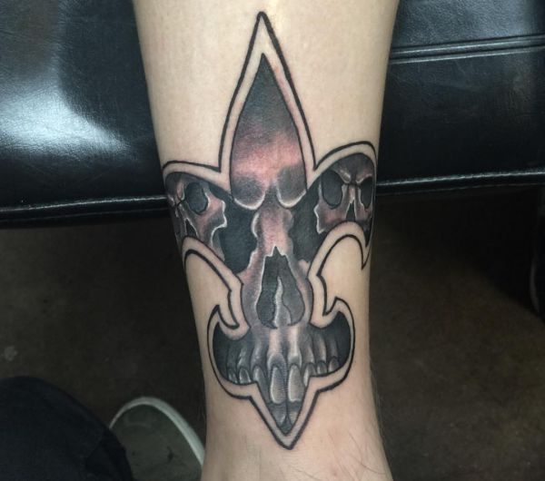 Crânio com desenho de tatuagem de fleur-de-lis na parte inferior da perna 