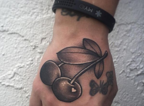 Tatuagem de cereja com o coração na mão 