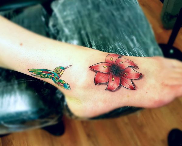 Tatuagem de pé de flores e beija-flores 