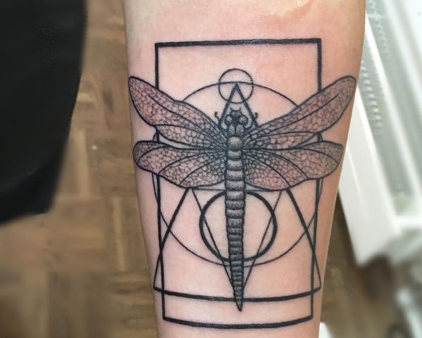Desenho geométrico de tatuagem de libélula no antebraço 