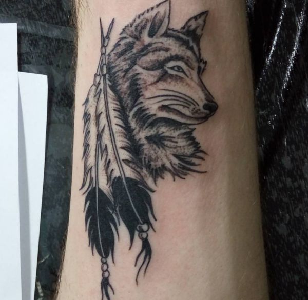 Lobo com tatuagem de pena no antebraço 