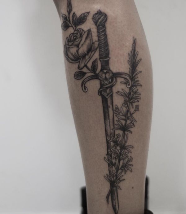 Tatuagem de espada com rosa na perna 