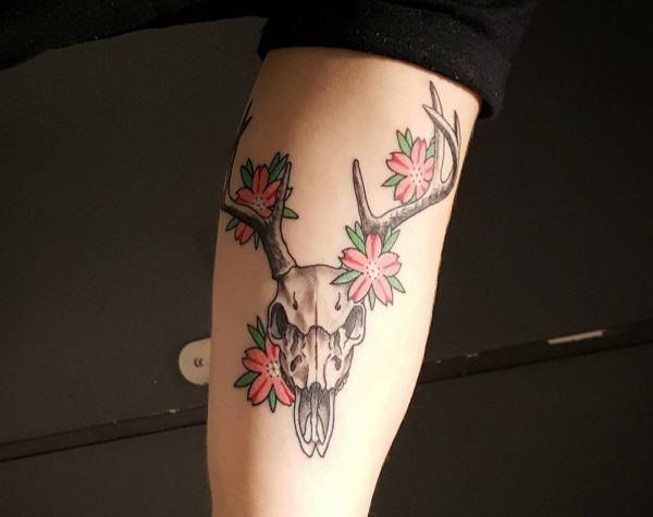 Crânio de veado com tatuagem de flor no braço 